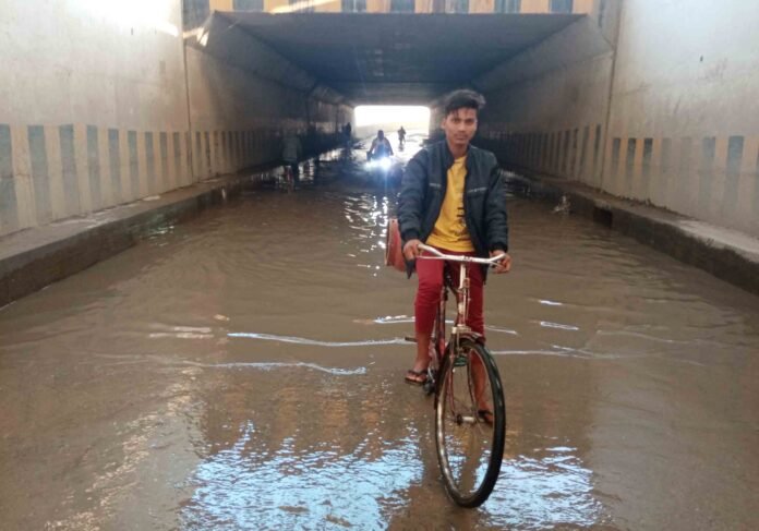 Young Writer: बिछियां अंडर पास पुलिया में जमा पानी से होकर गुजरते बाइक व साइकिल सवार।
