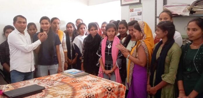 लालमनी बाबूलाल मौर्य विद्यालय में छात्राओं को मिठाई खिलाते शिक्षक।